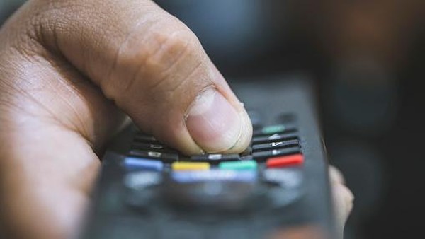 Close-up of a remote control sitting on a couch in an empty modern living room.