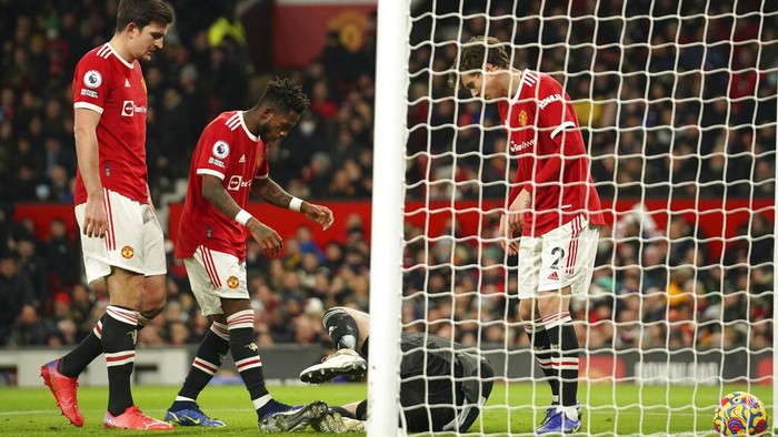 Manchester United players check on goalkeeper David de Gea as he lays in the goal mouth after conceding the opening goal during the English Premier League soccer match between Manchester United and Arsenal at Old Trafford stadium in Manchester, England, Thursday, Dec. 2, 2021. (AP Photo/Dave Thompson)