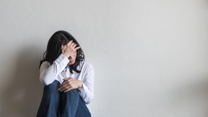 Anxiety disorder menopause woman, stressful depressed, panic attack person with mental health illness, headache and migraine sitting with back against wall on the floor in domestic home