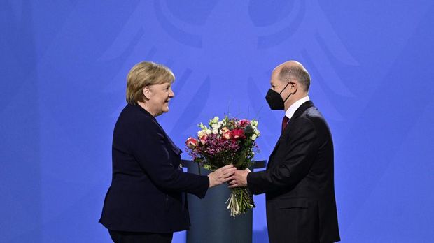 German Chancellor Olaf Scholz gives a bouquet of flowers to his predecessor Angela Merkel after she handed him over the office at the Chancellery in Berlin on December 8, 2021. - Members of the parliament elected Olaf Scholz as the country's next Chancellor, ushering in a new political era with the centre-left in charge. Together with the Greens and the liberal Free Democrats, Scholz's SPD managed in a far shorter time than expected to forge a coalition that aspires to make Germany greener and fairer. (Photo by John MACDOUGALL / AFP)