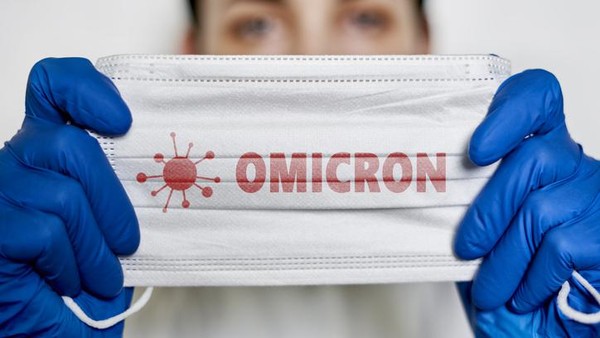 Female doctor holds a face mask with - Omicron variant text on it. Covid-19 new variant - Omicron. Omicron variant of coronavirus. SARS-CoV-2 variant of concern