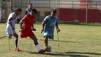 Para pemain berlomba melintasi lapangan dengan menggunakan tongkat, berdesak-desakan untuk mendapatkan bola sepak dan mengopernya ke depan dan ke belakang, kaki palsu mereka berjejer di pinggir lapangan di sebuah stadion di Jalur Gaza. 