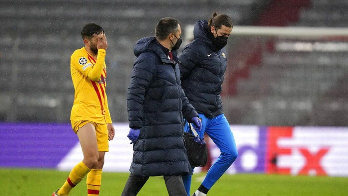 Barcelonas Jordi Alba, left, holds his face as he leaves the pitch after injuring during the Champions League group E soccer match between Bayern Munich and FC Barcelona in Munich, Germany, Wednesday, Dec. 8, 2021. (AP Photo/Matthias Schrader)