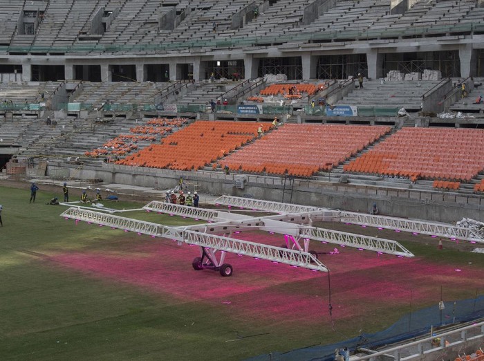 Pekerja menggunakan alat grass grow lighting untuk perawatan rumput lapangan Jakarta International Stadium (JIS) di Tanjung Priok, Jakarta, Kamis (9/12/2021). PT. Jakarta Propertindo (Jakpro) menggunakan teknologi pencahayaan ultraviolet (UV) tersebut untuk membantu pertumbuhan rumput hibrid (5 persen sintetis dan 95 persen rumput alami) lapangan stadion berkapasitas 82.000 penonton itu. ANTARA FOTO/Aditya Pradana Putra/rwa.
