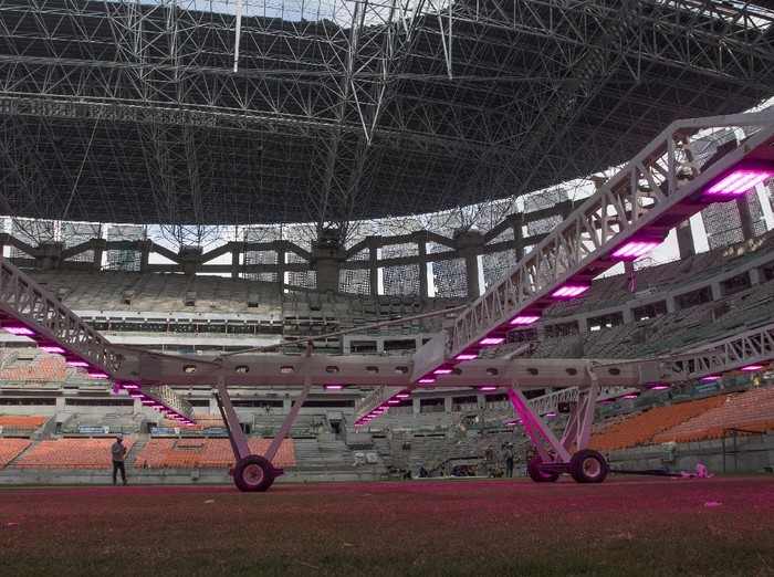 Pekerja menggunakan alat grass grow lighting untuk perawatan rumput lapangan Jakarta International Stadium (JIS) di Tanjung Priok, Jakarta, Kamis (9/12/2021). PT. Jakarta Propertindo (Jakpro) menggunakan teknologi pencahayaan ultraviolet (UV) tersebut untuk membantu pertumbuhan rumput hibrid (5 persen sintetis dan 95 persen rumput alami) lapangan stadion berkapasitas 82.000 penonton itu. ANTARA FOTO/Aditya Pradana Putra/rwa.