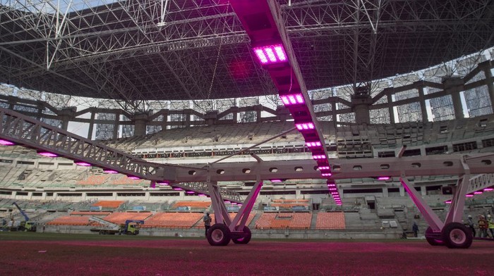 Pekerja menggunakan alat grass grow lighting untuk perawatan rumput lapangan Jakarta International Stadium (JIS) di Tanjung Priok, Jakarta, Kamis (9/12/2021). PT. Jakarta Propertindo (Jakpro) menggunakan teknologi pencahayaan ultraviolet (UV) tersebut untuk membantu pertumbuhan rumput hibrid (5 persen sintetis dan 95 persen rumput alami) lapangan stadion berkapasitas 82.000 penonton itu. ANTARA FOTO/Aditya Pradana Putra/rwa.