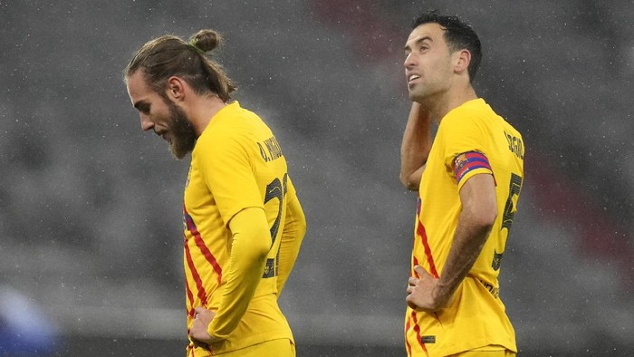 Barcelonas Oscar Mingueza, left, and Sergio Busquets stand on the pitch after the Champions League group E soccer match between Bayern Munich and FC Barcelona in Munich, Germany, Wednesday, Dec. 8, 2021. Bayern won 3-0. (AP Photo/Matthias Schrader)