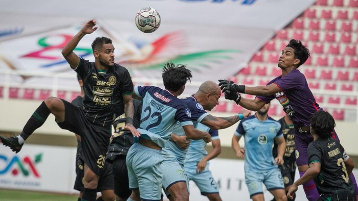 Penjaga gawang PSS Sleman Miswar Saputra (kanan) berusaha mengalau bola umpan silang yang mengarah ke pesepak bola Persela Lamongan Guilherme Felipe De Castro (kedua kanan) dan Riyatno Abiyoso (kedua kiri) pada pertandingan Liga I di Stadion Manahan, Solo, Jawa Tengah, Sabtu (11/12/2021). Pada pertandingan tersebut PSS Sleman dan Persela Lamongan bermain imbang 1-1. ANTARA FOTO/Mohammad Ayudha/aww.