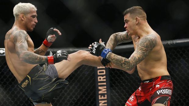 Charles Oliveira, left, tries to kick Dustin Poirier during a lightweight mixed martial arts title bout at UFC 269, Saturday, Dec. 11, 2021, in Las Vegas. (AP Photo/Chase Stevens)