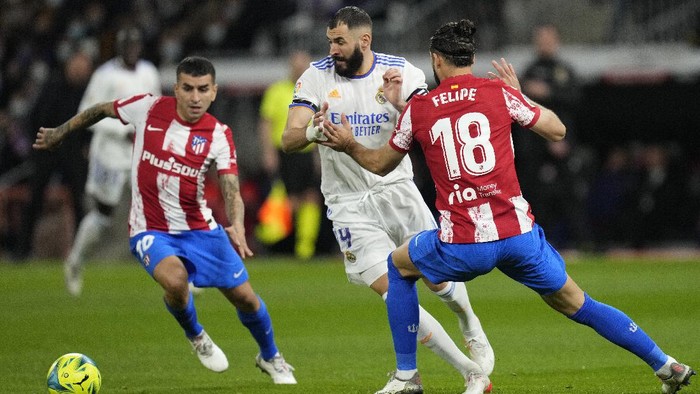 Real Madrids Karim Benzema, center, challenges for the ball with Atletico Madrids Felipe, right, and Angel Correa during the Spanish La Liga soccer match between Real Madrid and Atletico Madrid at Santiago Bernabeu stadium in Madrid, Spain, Sunday, Dec. 12, 2021. (AP Photo/Bernat Armangue)