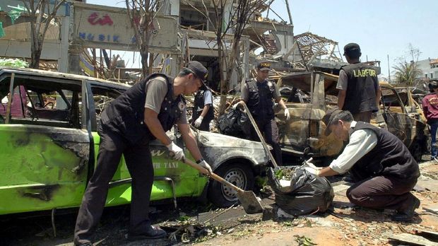 Bom Bali 1 pada 12 Oktober 2002 Indonesian policemen from the forensic and laboratory center work near the site of a 12 October car bombing that killed at least 190 people in the tourist area in Kuta, near Denpasar, on the island of Bali, 14 October 2002, in search of evidence. The huge car bomb ripped through two bars packed with foreign tourists, killing at least 190 and injured hundreds of others in the usually tranquil Indonesian island paradise. AFP PHOTO/Oka BUDHI (Photo by OKA BUDHI / AFP)