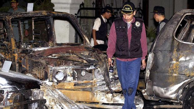 An Indonesian forensic policeman looks at burned-out cars outside the Kanisius Catholic school chapel in Jakarta 24 December 2000,  after several explosions rocked the area. At least seven people were killed and more than 30 injured in explosions detonated outside Christian churches across Indonesia, as Christian celebrated Christmas Eve mass inside.  AFP PHOTO/Weda (Photo by WEDA / AFP)