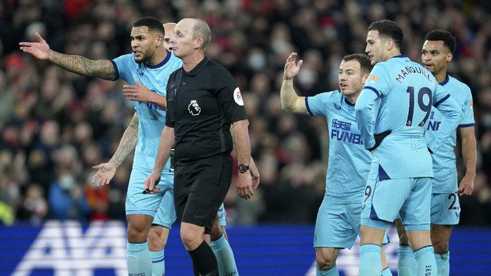 Referee Mike Dean, front, discusses with Newcastle players during the English Premier League soccer match between Liverpool and Newcastle United at Anfield stadium in Liverpool, England, Thursday, Dec. 16, 2021. (AP Photo/Jon Super)