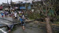 A resident carries bicycle over the toppled electrical post and tree caused by Typhoon Rai in Cebu city, central Philippines on Friday, Dec. 17, 2021. A powerful typhoon slammed into the southeastern Philippines on Thursday, toppling trees, ripping tin roofs and knocking down power as it blew across island provinces where nearly 100,000 people have been evacuated. (AP Photo/Jay Labra)\