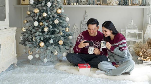 Asian Chinese couple decorating Christmas tree at home ready for Christmas celebration