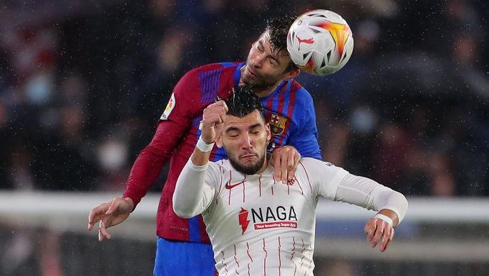 SEVILLE, SPAIN - DECEMBER 21: Rafa Mir of Sevilla battles for possession with Gerard Pique of FC Barcelona in the air during the LaLiga Santander match between Sevilla FC and FC Barcelona at Estadio Ramon Sanchez Pizjuan on December 21, 2021 in Seville, Spain. (Photo by Fran Santiago/Getty Images)
