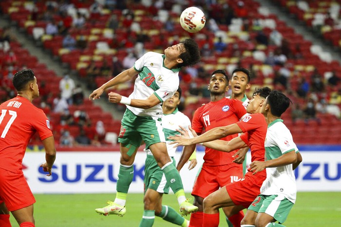 Alfeandra Dewangga Santosa of Indonesia, center, jumps to head the ball during the AFF Suzuki Cup 2020 semi-final first leg soccer match between Singapore and Indonesia in Singapore, Wednesday, Dec. 22, 2021. (AP Photo/Suhaimi Abdullah)