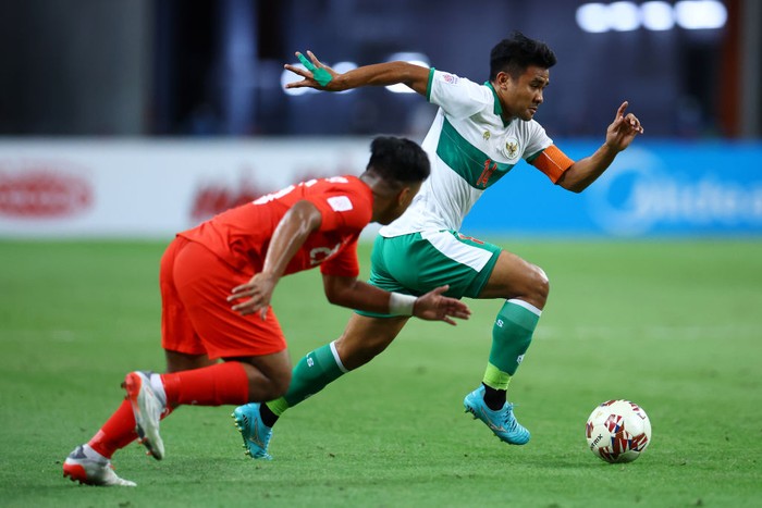 SINGAPORE, SINGAPORE - DECEMBER 22: Asnawi Mangkualam Bahar #14 of Indonesia controls the ball against Nur Adam Abdullah #25 of Singapore during the first half of the first leg of their AFF Suzuki Cup semifinal at the National Stadium on December 22, 2021 in Singapore. (Photo by Yong Teck Lim/Getty Images)