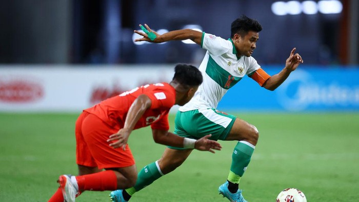 SINGAPORE, SINGAPORE - DECEMBER 22: Asnawi Mangkualam Bahar #14 of Indonesia controls the ball against Nur Adam Abdullah #25 of Singapore during the first half of the first leg of their AFF Suzuki Cup semifinal at the National Stadium on December 22, 2021 in Singapore. (Photo by Yong Teck Lim/Getty Images)