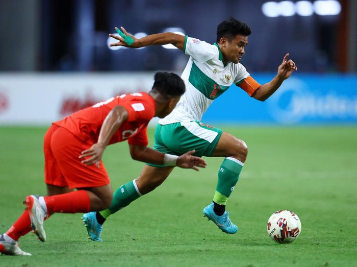 SINGAPORE, SINGAPORE - DECEMBER 22: Asnawi Mangkualam Bahar #14 of Indonesia controls the ball against Nur Adam Abdullah #25 of Singapore during the first half of the first leg of their AFF Suzuki Cup semifinal at the National Stadium on December 22, 2021 in Singapore. (Photo by Yong Teck Lim/Getty Images)