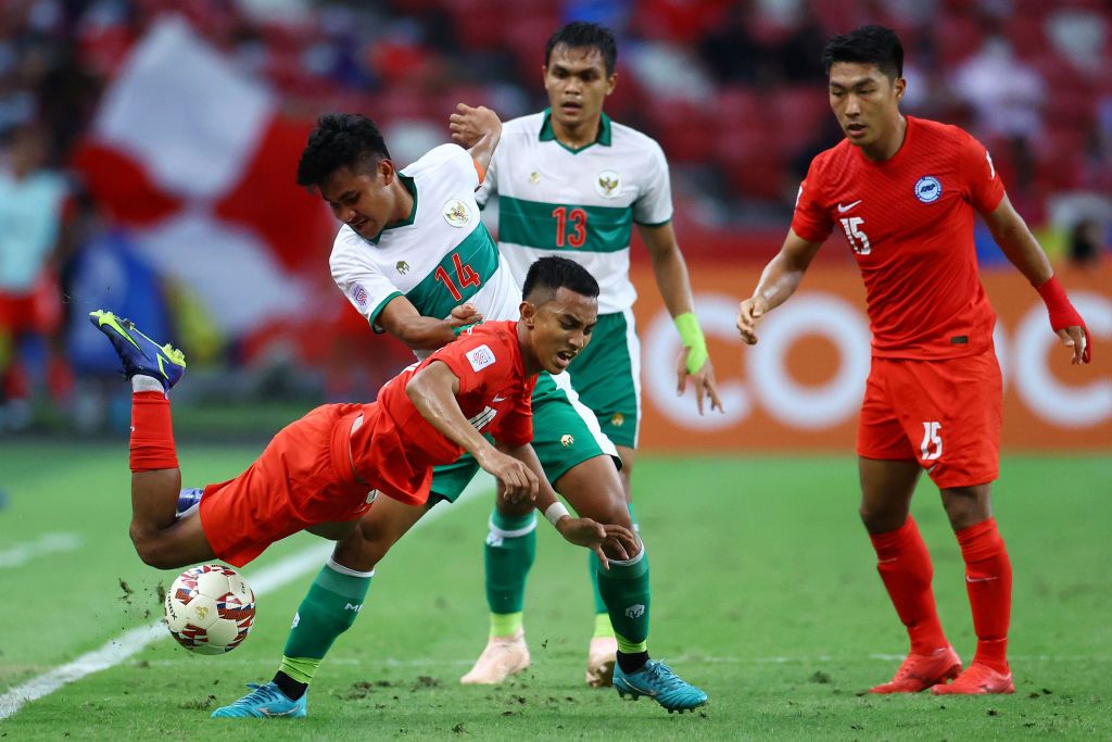 SINGAPORE, SINGAPORE - DECEMBER 22: Asnawi Mangkualam Bahar #14 of Indonesia controls the ball against Nur Adam Abdullah #25 of Singapore during the first half of the first leg of their AFF Suzuki Cup semifinal at the National Stadium on December 22, 2021 in Singapore. (Photo by Yong Teck Lim/Getty Images)
