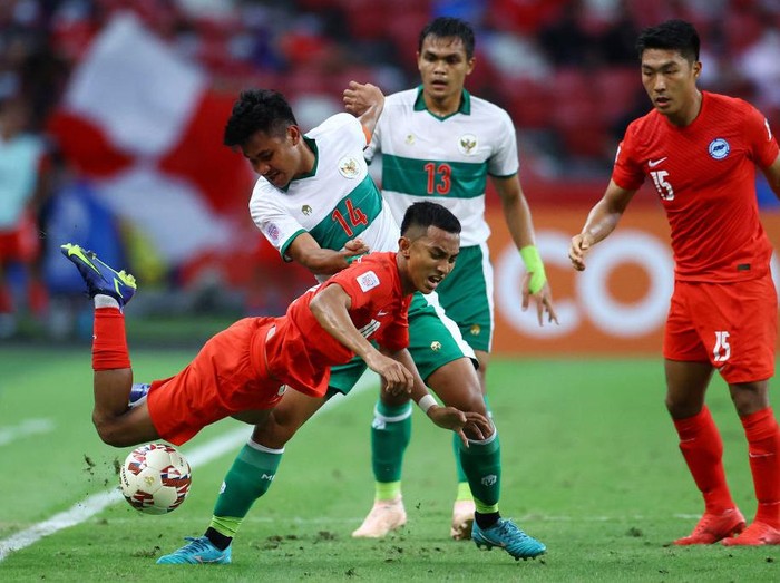 SINGAPORE, SINGAPORE - DECEMBER 22: Asnawi Mangkualam Bahar #14 of Indonesia controls the ball against Nur Adam Abdullah #25 of Singapore during the first half of the first leg of their AFF Suzuki Cup semifinal at the National Stadium on December 22, 2021 in Singapore. (Photo by Yong Teck Lim/Getty Images)