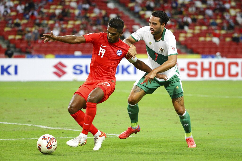 Hariss Harun of Singapore, left, and Ezra Harm Ruud Walian of Indonesia battle for the ball during the AFF Suzuki Cup 2020 semi-final first leg match between Singapore and Indonesia in Singapore, Wednesday, Dec. 22, 2021. (AP Photo/Suhaimi Abdullah)