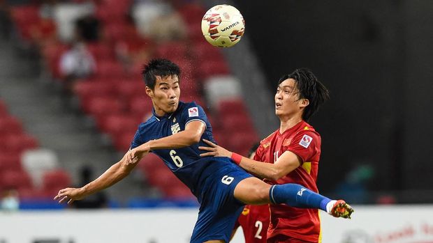 Thailand's Sarach Yooyen (L) fights for the ball with Vietnam's Nguyen Tuan Anh during the first leg of the AFF Suzuki Cup 2020 football semi-final match between Vietnam and Thailand at the National Stadium in Singapore on December 23, 2021. (Photo by Roslan RAHMAN / AFP)