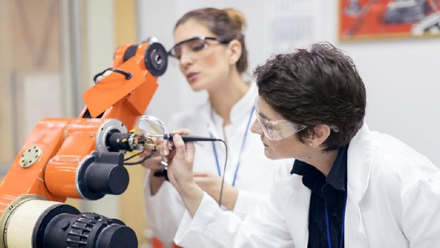 Female engineers repairing electronic machine in research lab