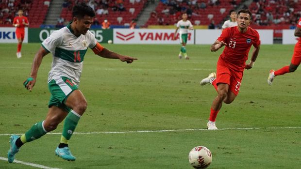 Pesepak bola Timnas Indonesia Asnawi Mangkualam (kiri) berusaha melewati hadangan pesepak bola Timnas Singapura Zulfahmi Arifin (kanan) dalam pertandingan Semi Final Leg 1 Piala AFF 2020 di National Stadium, Singapura, Rabu (22/12/2021). Pertandingan berakhir imbang 1-1. ANTARA FOTO/Humas PSSI/app/rwa.