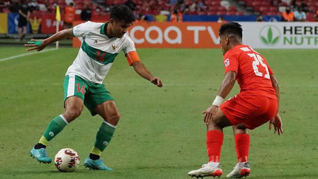 Pesepak bola Timnas Indonesia Asnawi Mangkualam (kiri) berusaha melewati hadangan pesepak bola Timnas Singapura Nur Adam Abdullah (kanan) dalam pertandingan Semi Final Leg 1 Piala AFF 2020 di National Stadium, Singapura, Rabu (22/12/2021).  Pertandingan berakhir imbang 1-1. ANTARA FOTO/Humas PSSI/app/rwa.