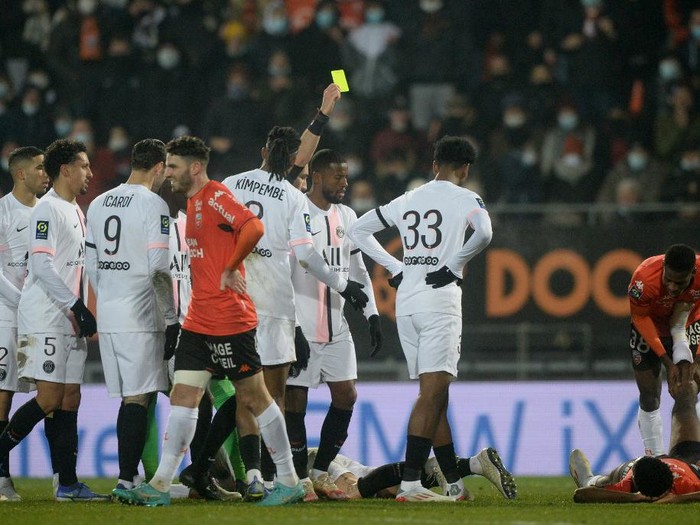 French referee Jeremie Pignard (C) shows a yellow card to Paris Saint-Germain's Spanish defender Sergio Ramos during the French L1 football match between FC Lorient and Paris Saint-Germain at the Yves Allainmat-Le Moustoir Stadium in Lorient, western France, on December 22, 2021. (Photo by JEAN-FRANCOIS MONIER / AFP)