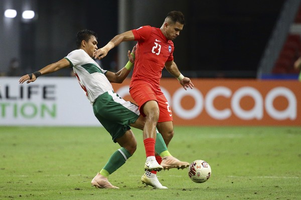Rachmat Irianto of Indonesia, left, and Zulfahmi Arifin of Singapore compete for the ball during the AFF Suzuki Cup 2020 semi-final first leg soccer match between Singapore and Indonesia in Singapore, Wednesday, Dec. 22, 2021. (AP Photo/Suhaimi Abdullah)