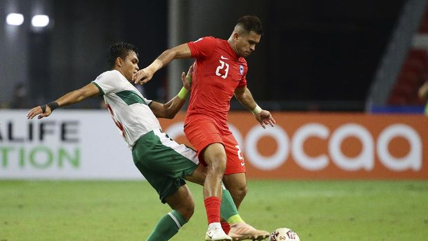 Rachmat Irianto of Indonesia, left, and Zulfahmi Arifin of Singapore compete for the ball during the AFF Suzuki Cup 2020 semi-final first leg soccer match between Singapore and Indonesia in Singapore, Wednesday, Dec. 22, 2021. (AP Photo/Suhaimi Abdullah)