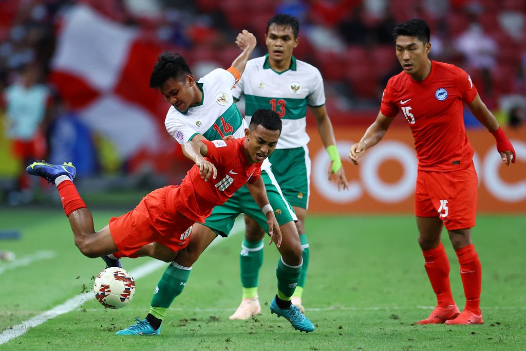 SINGAPORE, SINGAPORE - DECEMBER 22: Faris Ramli #10 of Singapore falls as he competes for the ball against Asnawi Mangkualam Bahar #14 of Indonesia during the first half of the first leg of their AFF Suzuki Cup semifinal at the National Stadium on December 22, 2021 in Singapore. (Photo by Yong Teck Lim/Getty Images)