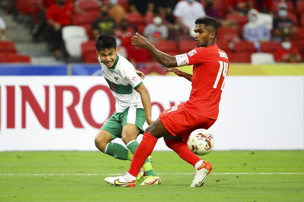 Witan Sulaeman of Indonesia, left, shoots past Hariss Harun of Singapore during the AFF Suzuki Cup 2020 semi-final first leg soccer match between Singapore and Indonesia in Singapore, Wednesday, Dec. 22, 2021. (AP Photo/Suhaimi Abdullah)