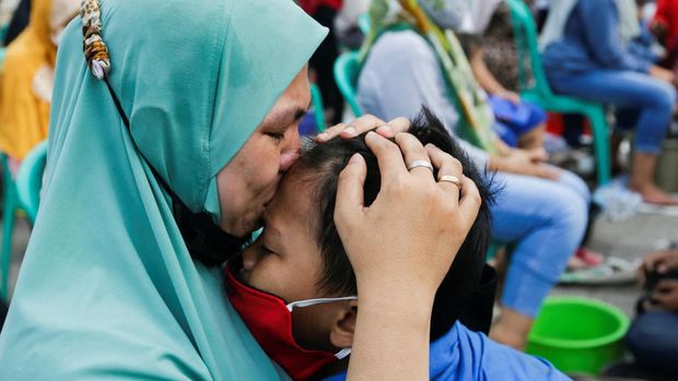 A woman kisses her child at an event to celebrate Indonesia's Mother's Day in Jakarta, Indonesia, December 22, 2021. REUTERS/Ajeng Dinar Ulfiana