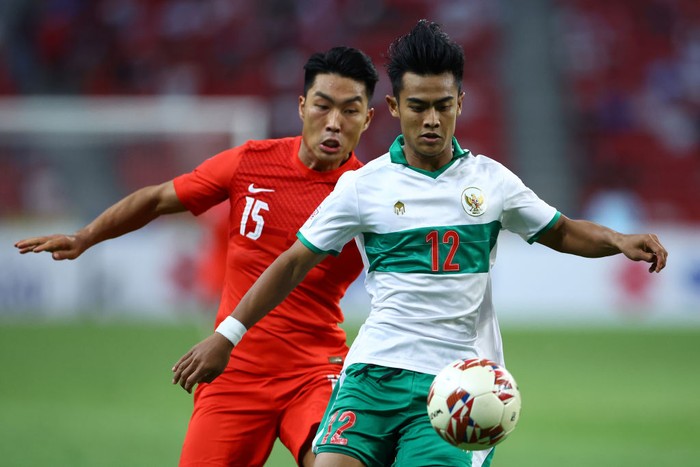 SINGAPORE, SINGAPORE - DECEMBER 22: Pratama Arhan Alif Rifai #12 of Indonesia controls the ball against Song Ui-Young #15 of Singapore during the second half of the first leg of their AFF Suzuki Cup semifinal at the National Stadium on December 22, 2021 in Singapore. (Photo by Yong Teck Lim/Getty Images)