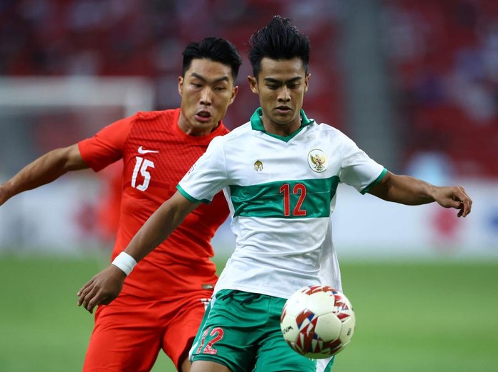 SINGAPORE, SINGAPORE - DECEMBER 22: Pratama Arhan Alif Rifai #12 of Indonesia controls the ball against Song Ui-Young #15 of Singapore during the second half of the first leg of their AFF Suzuki Cup semifinal at the National Stadium on December 22, 2021 in Singapore. (Photo by Yong Teck Lim/Getty Images)