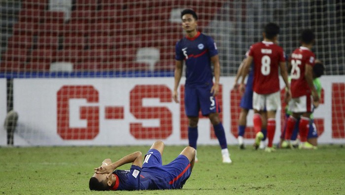 Faris Ramli of Singapore, foreground, reacts at the final whistle during the AFF Suzuki Cup 2020 semi-final second leg match between Indonesia and Singapore in Singapore, Saturday, Dec. 25, 2021. (AP Photo/Suhaimi Abdullah)