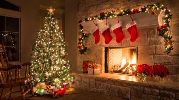 Glowing Christmas fireplace and living room, with tree, and stockings hanging from mantel by fireplace.Waiting for Santa.