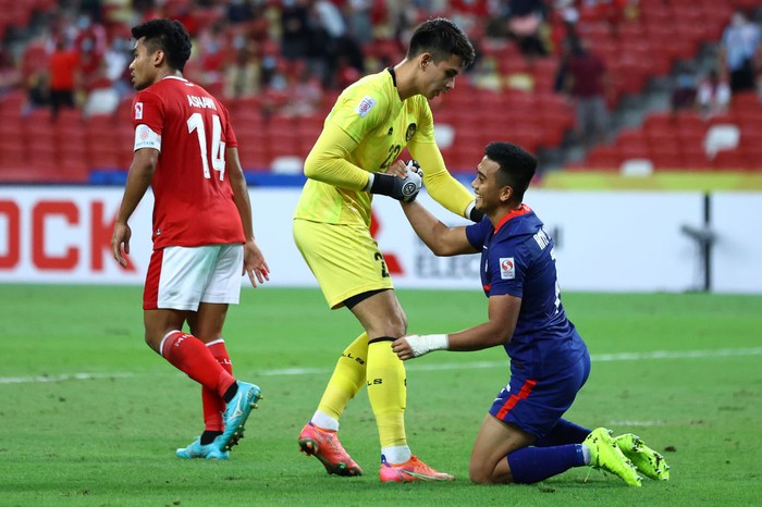 SINGAPORE, SINGAPORE - DECEMBER 25: Amy Recha #7 of Singapore is helped up by goalkeeper Nadeo Arga Winata #23 of Indonesia after a missed shot attempt during the first half of the second leg of their AFF Suzuki Cup semifinal at the National Stadium on December 25, 2021 in Singapore. (Photo by Yong Teck Lim/Getty Images)