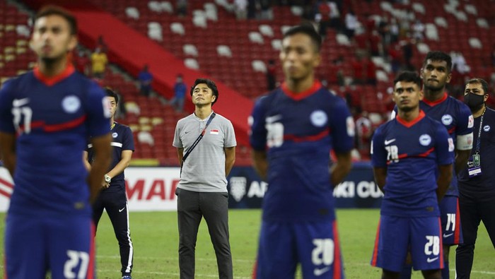 Singapore head coach, Tatsuma Yoshida, second left, stands at attention with the players as the supporters sing the national anthem after the final whistle during the AFF Suzuki Cup 2020 semi-final second leg match between Indonesia and Singapore in Singapore, Saturday, Dec. 25, 2021. (AP Photo/Suhaimi Abdullah)