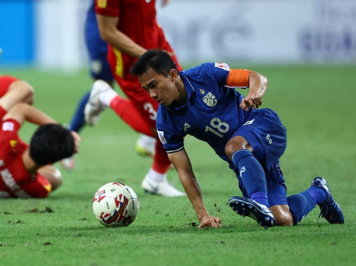 SINGAPORE, SINGAPORE - DECEMBER 23: Chanathip Songkrasin #18 of Thailand controls the ball after a tackle by Nguyen Hoang Duc #14 of Vietnam during the second half of the first leg of their AFF Suzuki Cup semifinal at the National Stadium on December 23, 2021 in Singapore. (Photo by Yong Teck Lim/Getty Images)