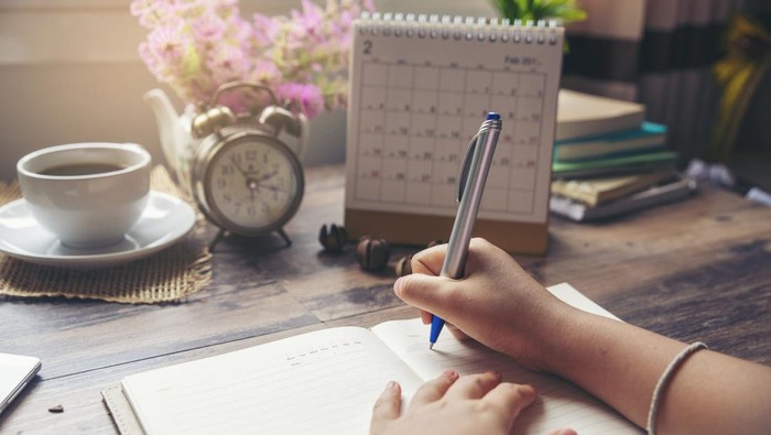 Ilustrasi Jadwal Cuti On 2019 Calendar book,Femalehand of planner writing daily appointment.Woman mark and noted schedule(holiday trip) on diary at office desk.Calendar reminder event for planner concept