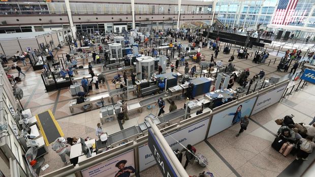 Omricon Tunda Ratusan Penerbangan di AS Travelers queue up at the south security checkpoint in the terminal of Denver International Airport Sunday, Dec. 26, 2021, in Denver. Airlines cancelled hundreds of flights Sunday, citing staffing problems tied to COVID-19 to extend the nation's travel problems beyond Christmas. (AP Photo/David Zalubowski)
