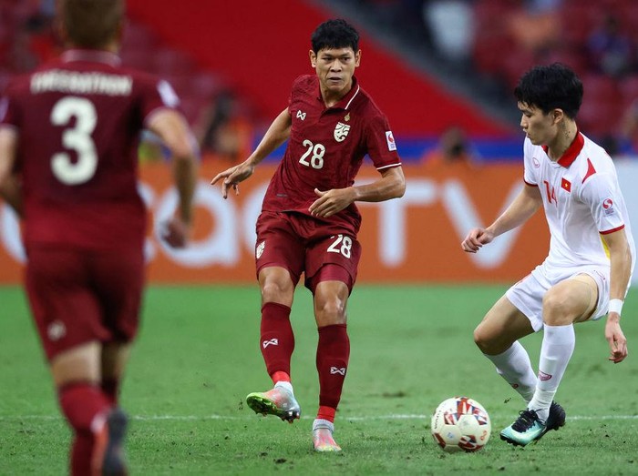 SINGAPORE, SINGAPORE - DECEMBER 26: Pokklaw Anan #28 of Thailand passes the ball against Nguyen Hoang Duc #14 of Vietnam during the second half of the second leg of their AFF Suzuki Cup semifinal at the National Stadium on December 26, 2021 in Singapore. (Photo by Yong Teck Lim/Getty Images)