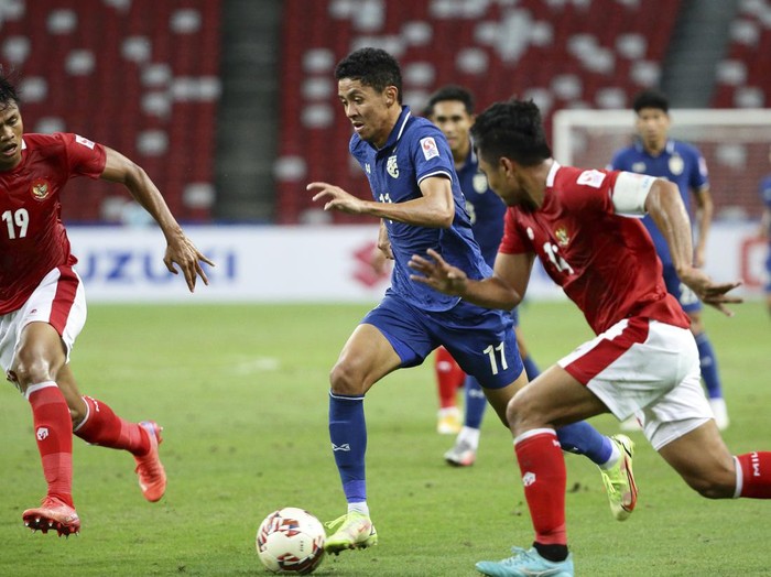 Supachok Sarachat of Thailand, right, controls the ball against Rachmat Irianto of Indonesia during the AFF Suzuki Cup 2020 final first leg soccer match between Indonesia and Thailand in Singapore, Wednesday, Dec. 29, 2021. (AP Photo/Suhaimi Abdullah)