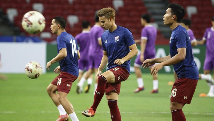 Theerathon Bunmathan of Thailand, center, warms up on the pitch ahead of the AFF Suzuki Cup 2020 semi-final second leg match between Thailand and Vietnam in Singapore, Sunday, Dec. 26, 2021. (AP Photo/Suhaimi Abdullah)