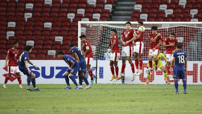 Indonesia players jump to block the free kick from Tristan Do of Thailand, left, during the AFF Suzuki Cup 2020 final first leg soccer match between Indonesia and Thailand in Singapore, Wednesday, Dec. 29, 2021. (AP Photo/Suhaimi Abdullah)